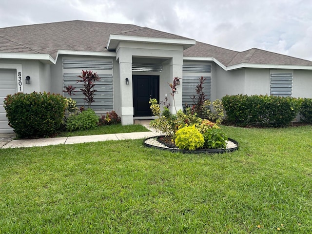 view of front facade featuring a garage, a front lawn, roof with shingles, and stucco siding