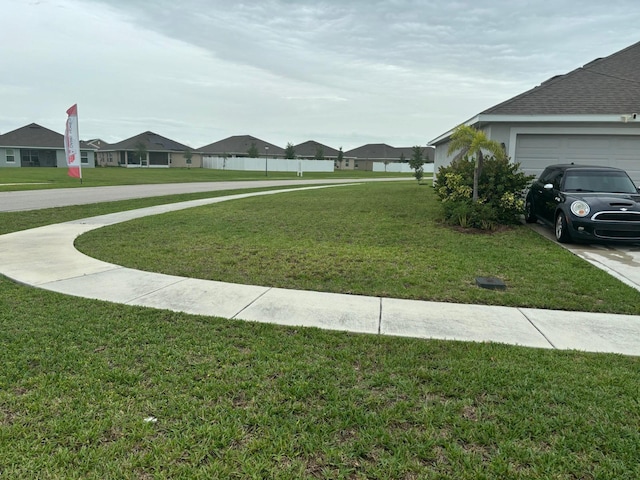 view of yard featuring an attached garage and a residential view