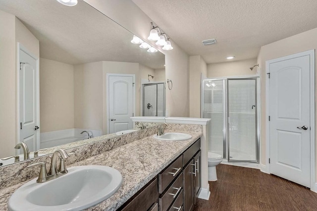 full bath with double vanity, wood finished floors, a stall shower, and a sink