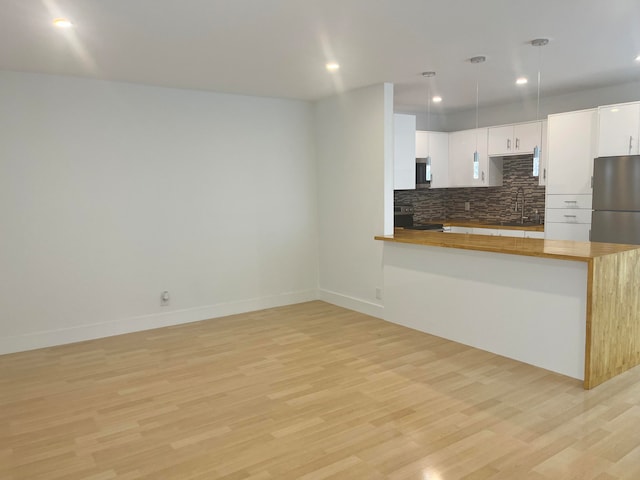 kitchen featuring white cabinetry, stainless steel appliances, decorative light fixtures, and light wood-type flooring