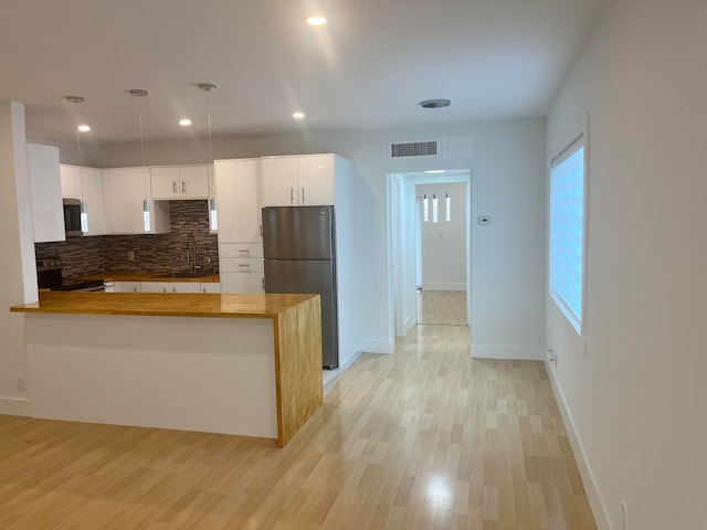 kitchen with kitchen peninsula, appliances with stainless steel finishes, white cabinetry, and hanging light fixtures