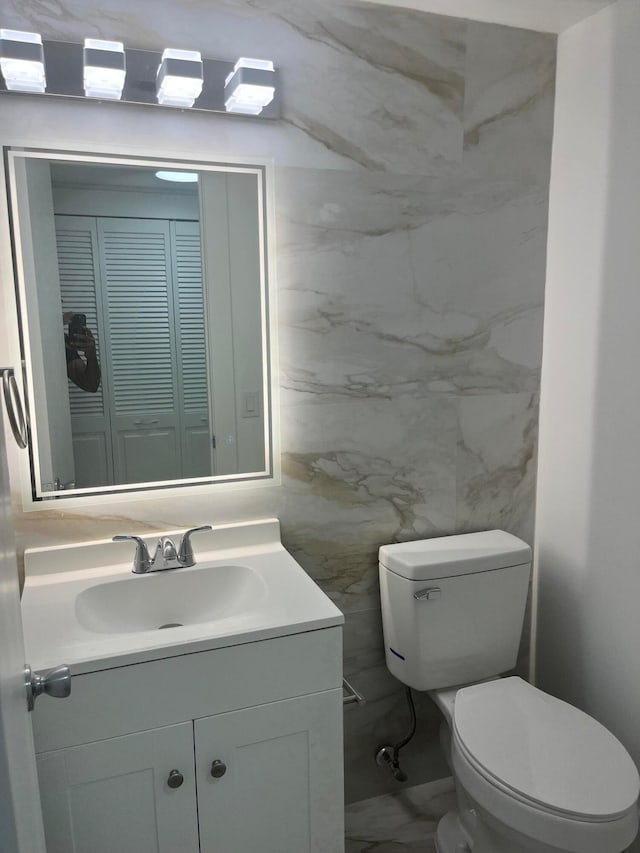 bathroom featuring vanity, tile walls, and toilet