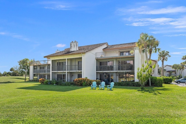 3500 Twin Lakes Ter Unit 106, Fort Pierce, FL 34951 - rear view of house featuring a yard, stucco siding, a chimney, and a balcony
