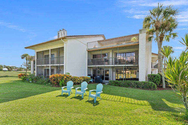 back of property featuring a balcony and a lawn