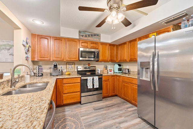 kitchen featuring light wood-type flooring, light stone countertops, sink, and stainless steel appliances