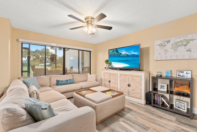 living room featuring ceiling fan, a textured ceiling, and light hardwood / wood-style flooring