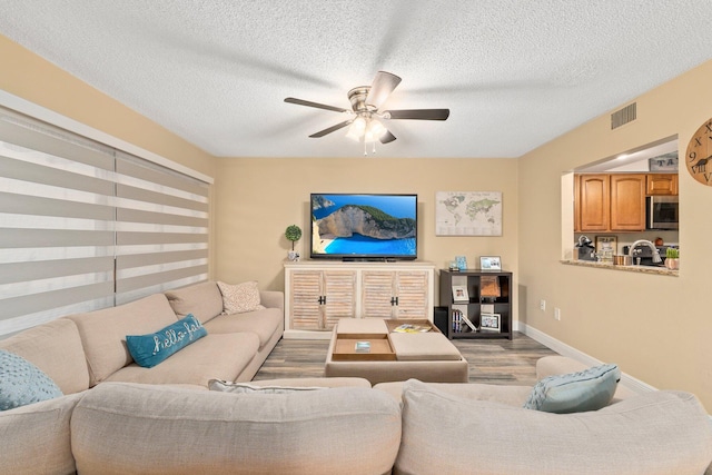 living room featuring a textured ceiling, wood-type flooring, sink, and ceiling fan