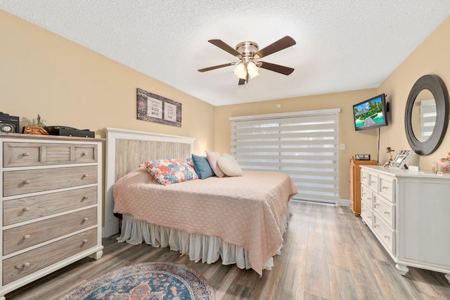 bedroom featuring ceiling fan, hardwood / wood-style flooring, and a textured ceiling