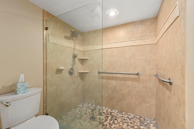 bathroom featuring toilet and a shower with shower door