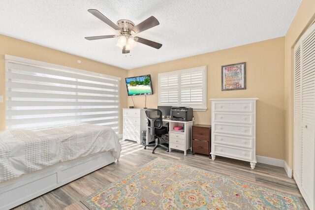 bedroom featuring a textured ceiling, hardwood / wood-style floors, ceiling fan, and a closet