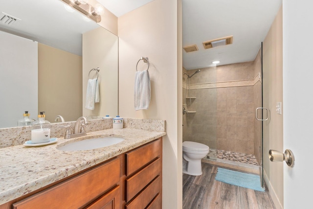 bathroom with wood-type flooring, vanity, toilet, and an enclosed shower