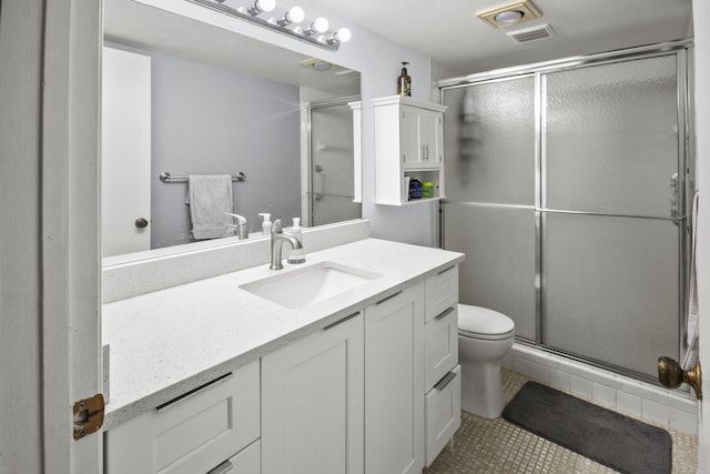 bathroom featuring tile patterned flooring, vanity, a shower with door, and toilet