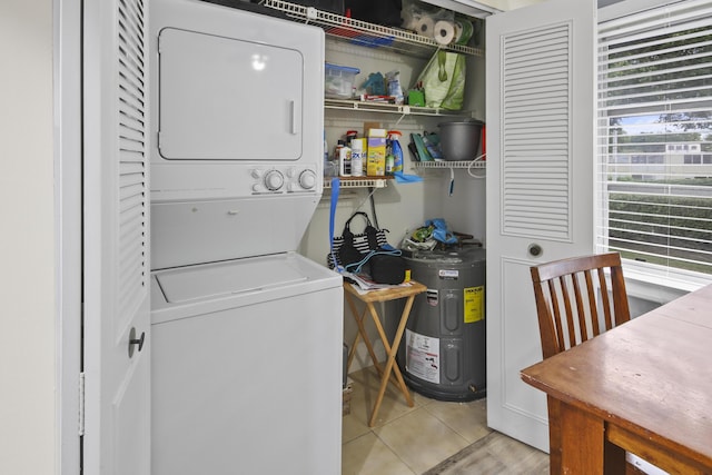 laundry area with stacked washer / dryer, water heater, and light tile patterned floors