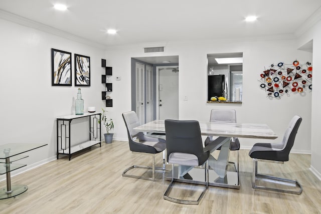 dining area featuring ornamental molding and light wood-type flooring