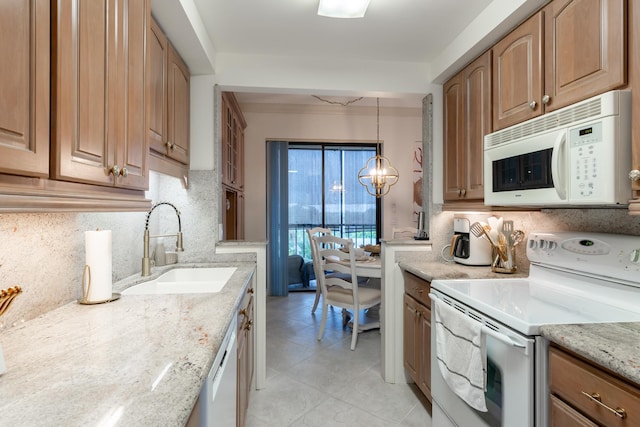 kitchen featuring light stone countertops, sink, hanging light fixtures, an inviting chandelier, and white appliances