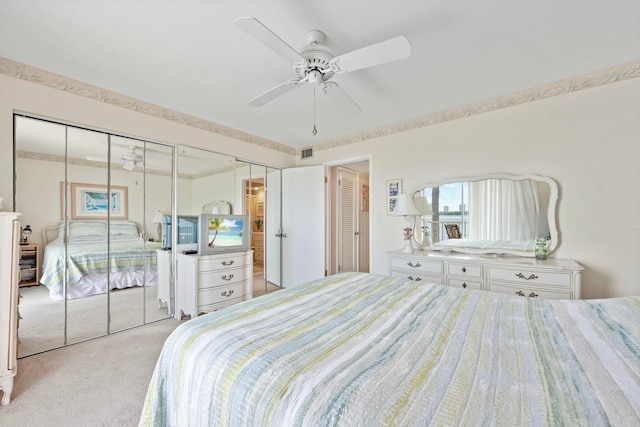 bedroom with ceiling fan, light colored carpet, and two closets