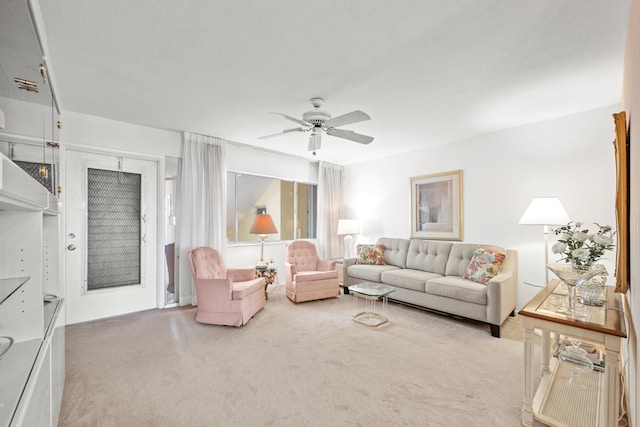 carpeted living room featuring ceiling fan and a textured ceiling