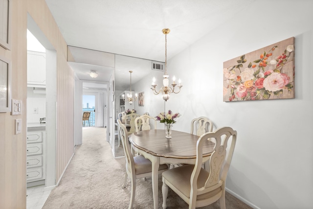 dining space with light carpet and a chandelier