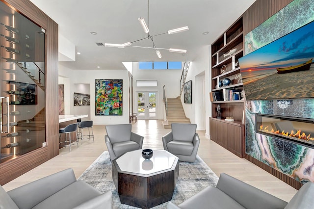 living room with light hardwood / wood-style floors, french doors, a fireplace, and a chandelier