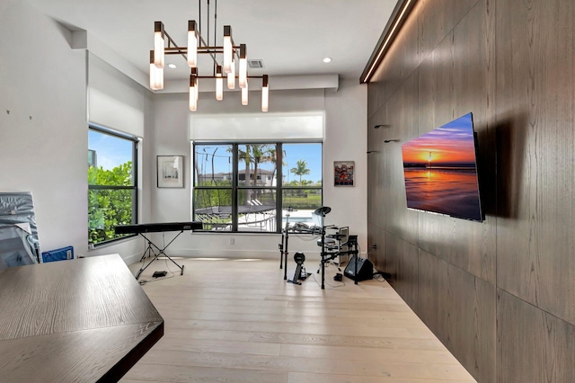 exercise area with an inviting chandelier and light hardwood / wood-style flooring