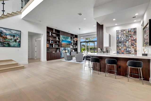 kitchen featuring decorative light fixtures, kitchen peninsula, a breakfast bar area, and light hardwood / wood-style flooring