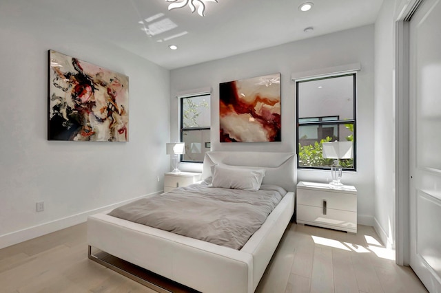 bedroom with multiple windows, a closet, and light hardwood / wood-style floors