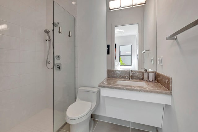 bathroom with tile patterned flooring, vanity, toilet, and tiled shower