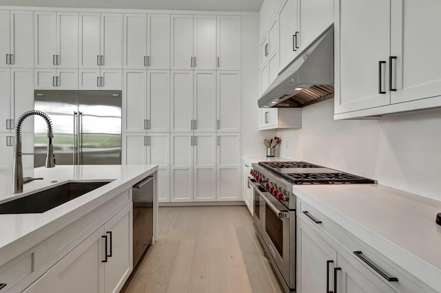 kitchen featuring sink, white cabinets, stainless steel appliances, and light hardwood / wood-style floors