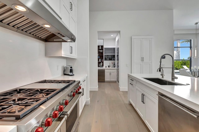 kitchen featuring white cabinetry, sink, stainless steel appliances, extractor fan, and light wood-type flooring