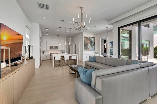 living room with light wood-type flooring, an inviting chandelier, and plenty of natural light