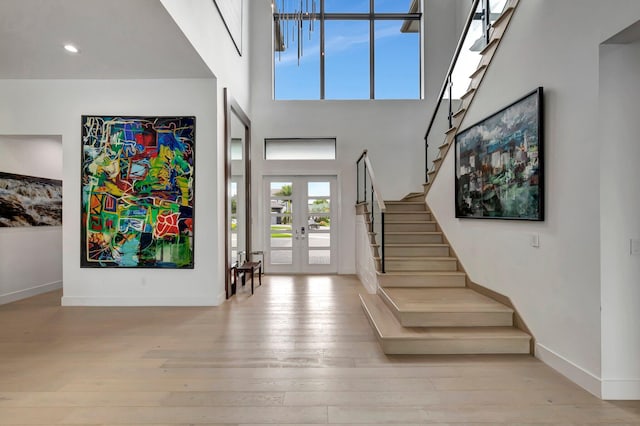 entryway featuring french doors, light hardwood / wood-style floors, and a high ceiling