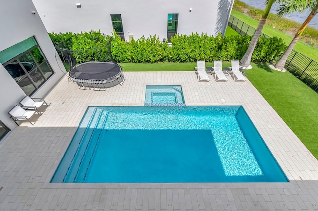 view of swimming pool with a patio area, a trampoline, and a yard