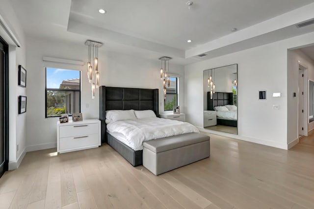 bedroom featuring a raised ceiling and light hardwood / wood-style flooring