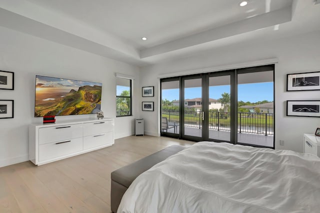 bedroom featuring a tray ceiling, access to exterior, french doors, and light hardwood / wood-style floors