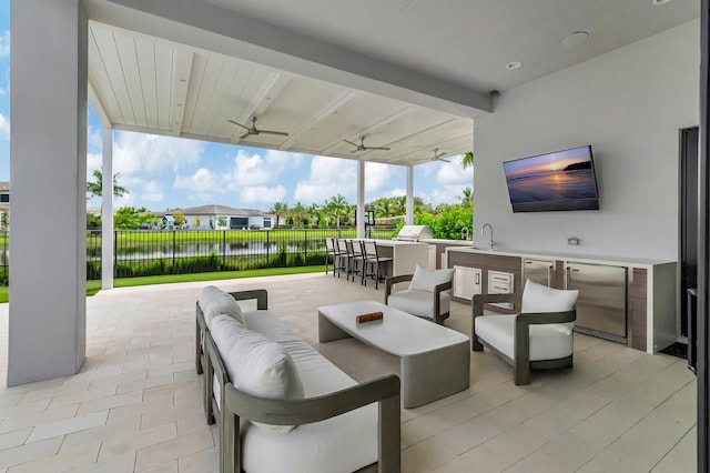 view of patio / terrace featuring an outdoor living space, a water view, an outdoor bar, ceiling fan, and exterior kitchen