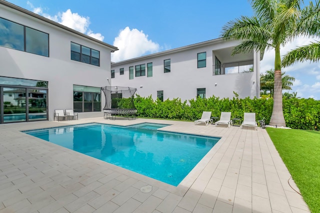 view of pool with a patio area, an in ground hot tub, and a trampoline