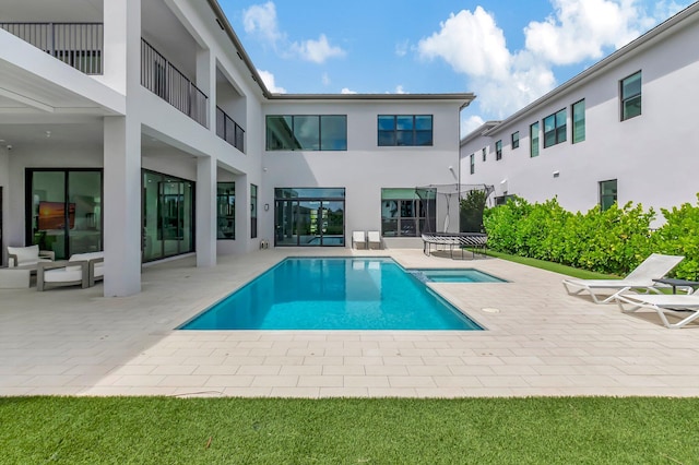 view of swimming pool featuring an in ground hot tub, a patio, and a trampoline