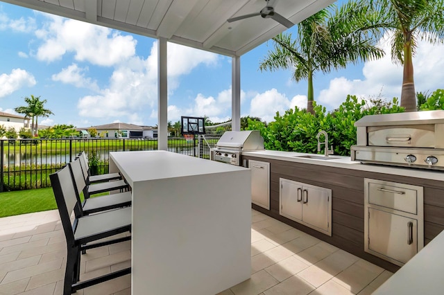 view of patio featuring ceiling fan, area for grilling, a water view, and an outdoor wet bar