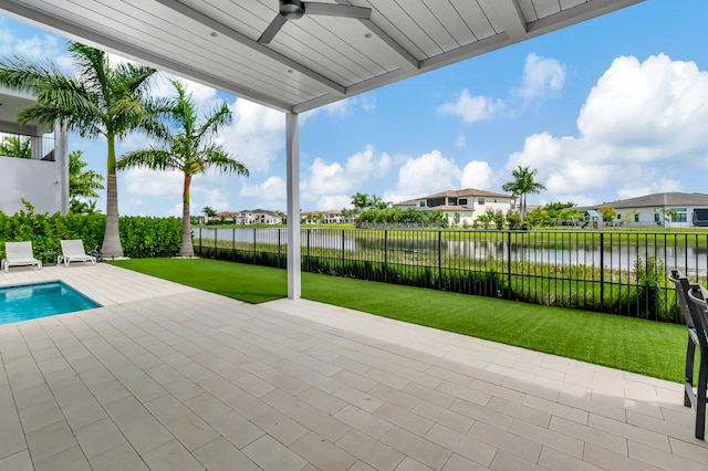 exterior space with a water view, ceiling fan, a patio area, and a lawn