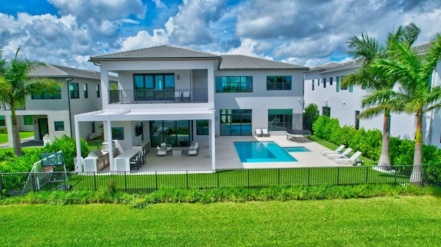 back of property featuring a lawn, an outdoor hangout area, a balcony, a fenced in pool, and a patio area