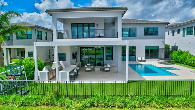 back of property featuring outdoor lounge area, a fenced in pool, a balcony, exterior kitchen, and a patio