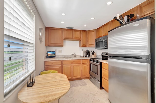 kitchen with appliances with stainless steel finishes, sink, and light tile patterned floors