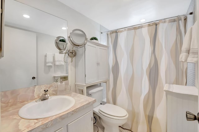 bathroom with walk in shower, vanity, and toilet