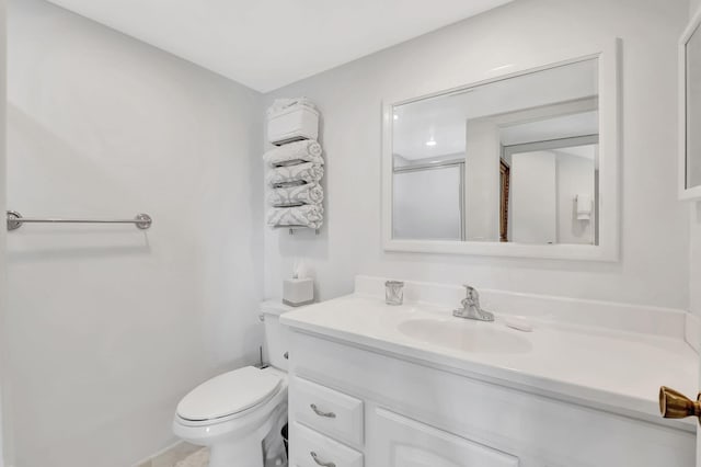 bathroom featuring a shower with door, vanity, and toilet