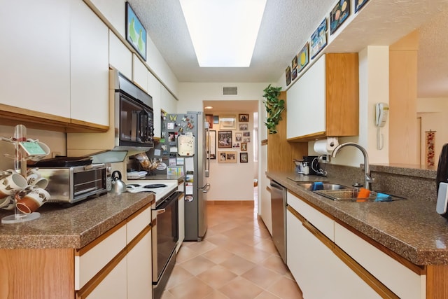 kitchen featuring a textured ceiling, sink, white cabinetry, stainless steel appliances, and a skylight