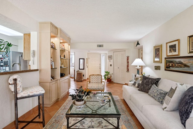 living room with a textured ceiling and light tile patterned flooring