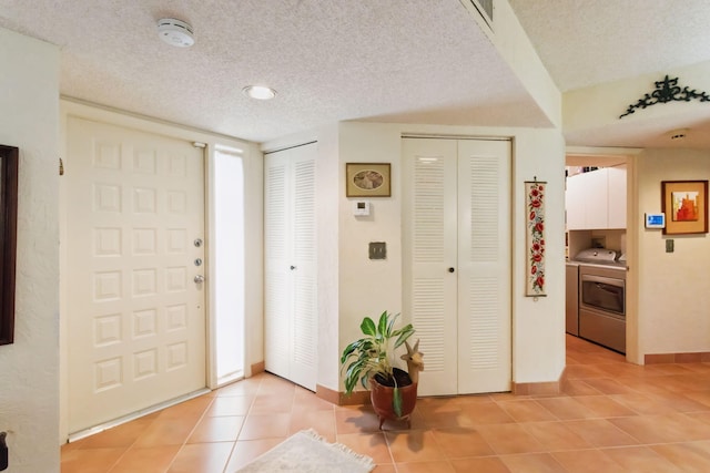 tiled foyer entrance featuring a textured ceiling and washer and clothes dryer