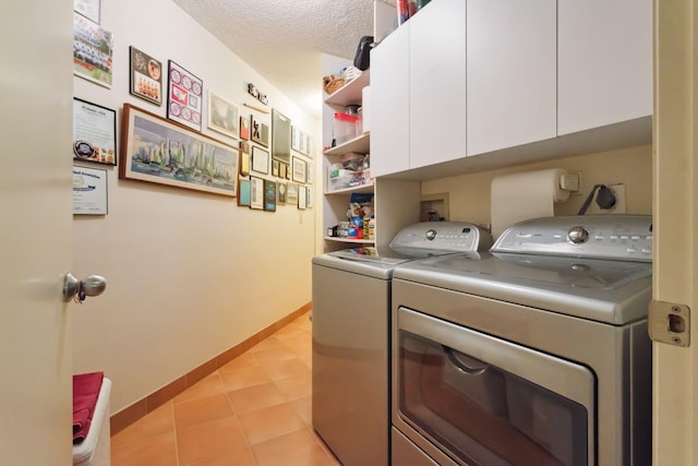 laundry room featuring a textured ceiling, washer and clothes dryer, light tile patterned floors, and cabinets