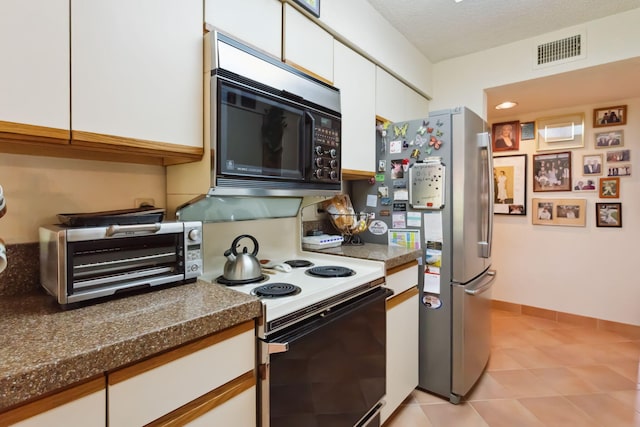 kitchen with a textured ceiling, white cabinetry, stainless steel refrigerator, electric stove, and dark stone counters