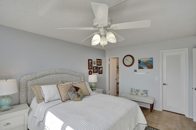 bedroom with a textured ceiling, light tile patterned floors, and ceiling fan